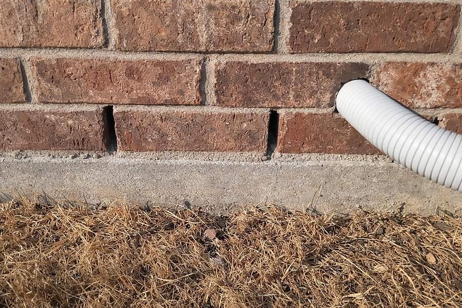 The bottom course of a brick veneer wall with open weep gaps in the mortar joints