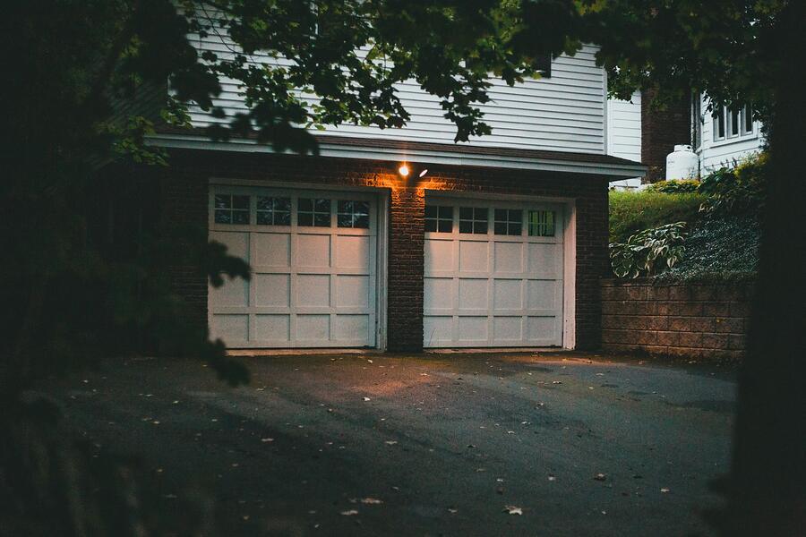 A suburban garage door at dusk, whose bottom corners are a common rodent entry