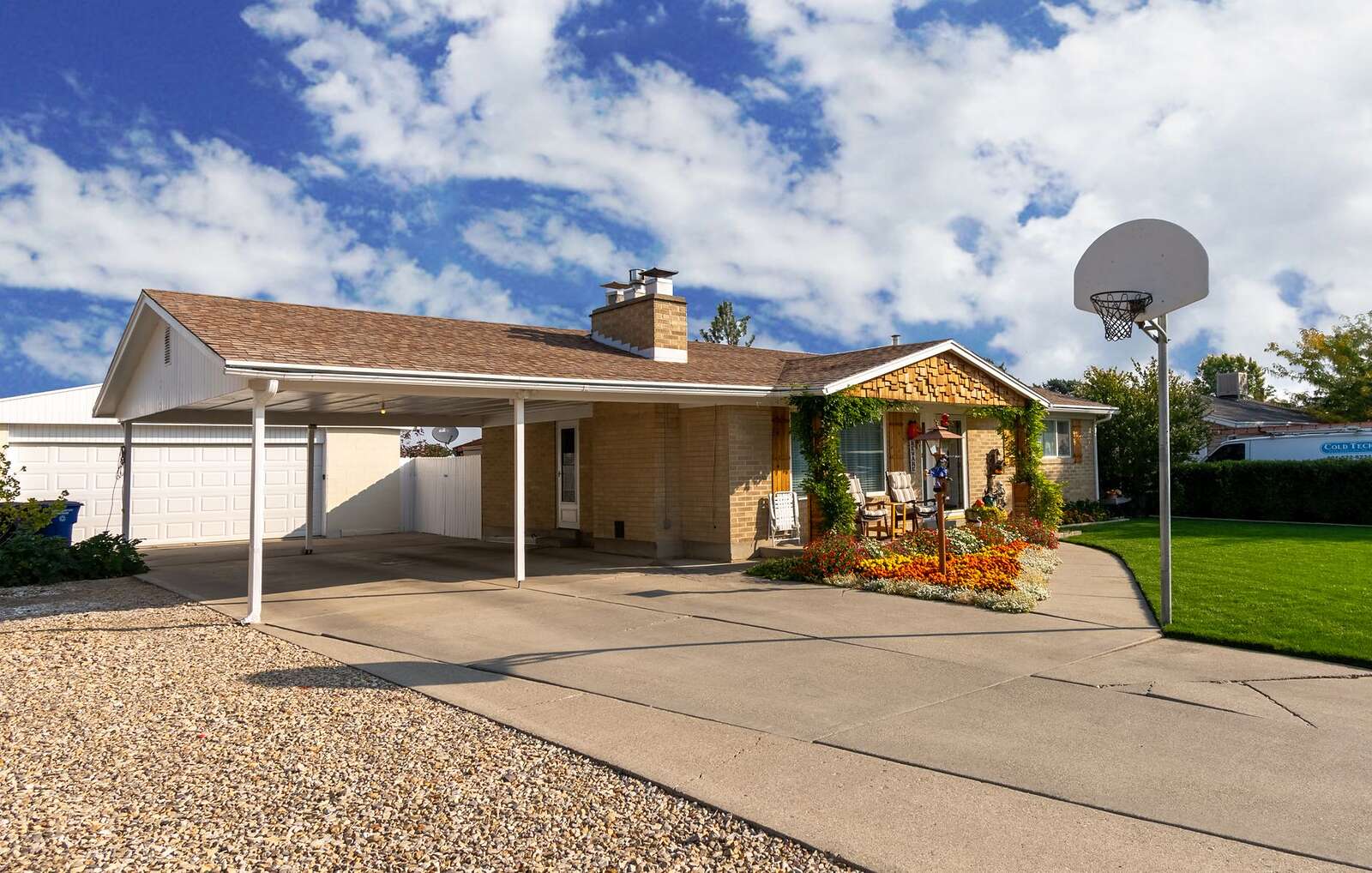 A single-story brick house with a carport, a basketball hoop and a flower bed
