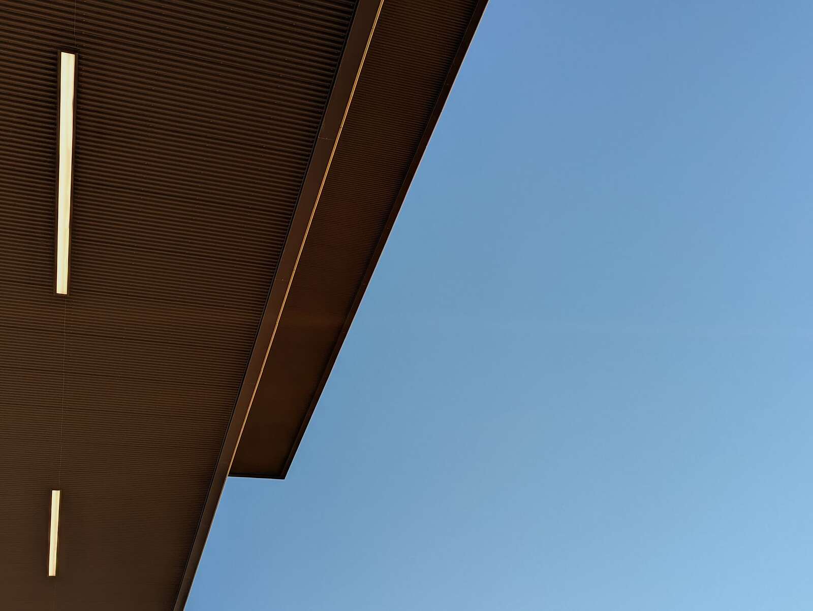 The underside of a soffit and fascia seen from below against a blue sky